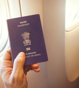 detail of passenger's hand holding indian passport on the airplane
